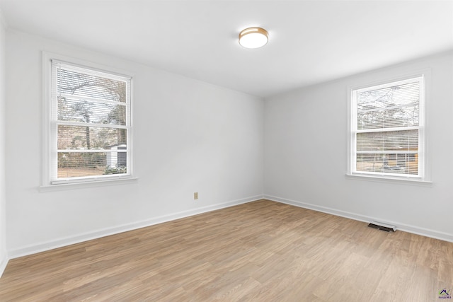 spare room featuring a wealth of natural light and light hardwood / wood-style floors