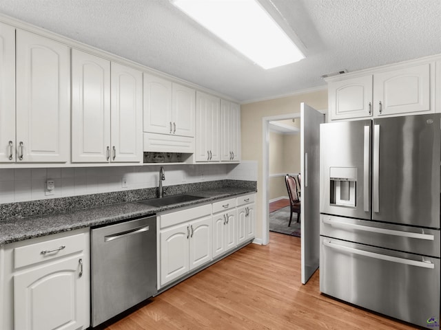 kitchen with sink, white cabinetry, light hardwood / wood-style flooring, appliances with stainless steel finishes, and backsplash