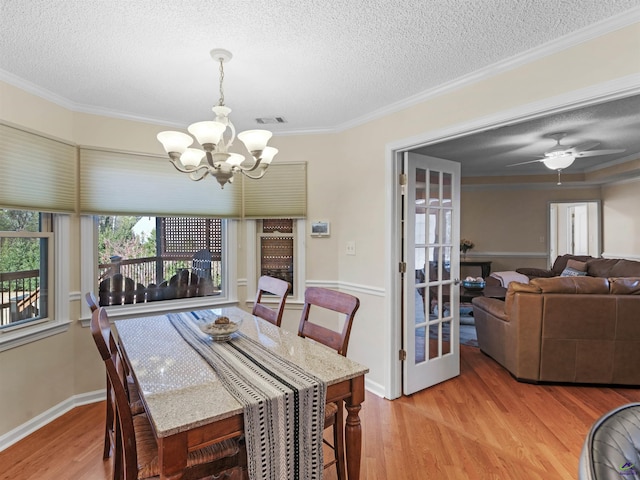 dining room featuring ornamental molding, ceiling fan with notable chandelier, a textured ceiling, and light wood-type flooring