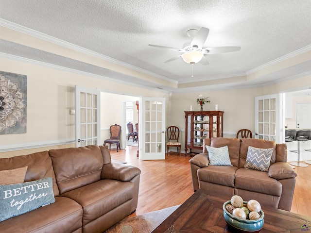 living room featuring french doors, ceiling fan, a textured ceiling, and light wood-type flooring