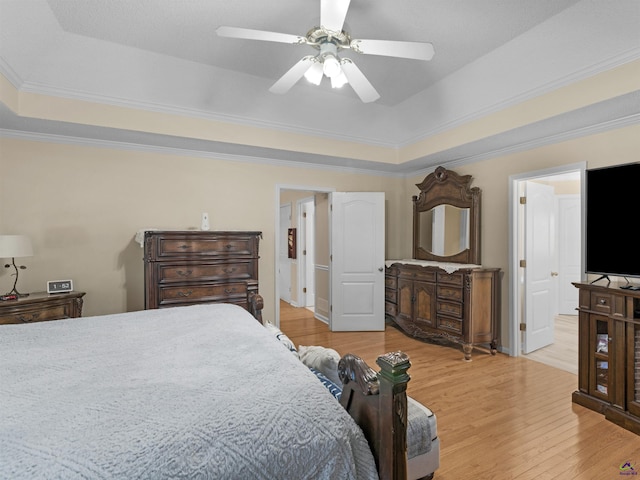 bedroom with crown molding, a tray ceiling, light hardwood / wood-style floors, and ceiling fan