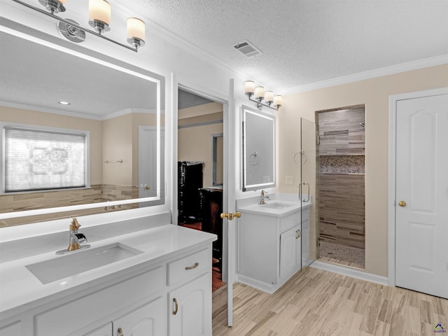 bathroom with crown molding, a textured ceiling, vanity, a shower with door, and hardwood / wood-style floors