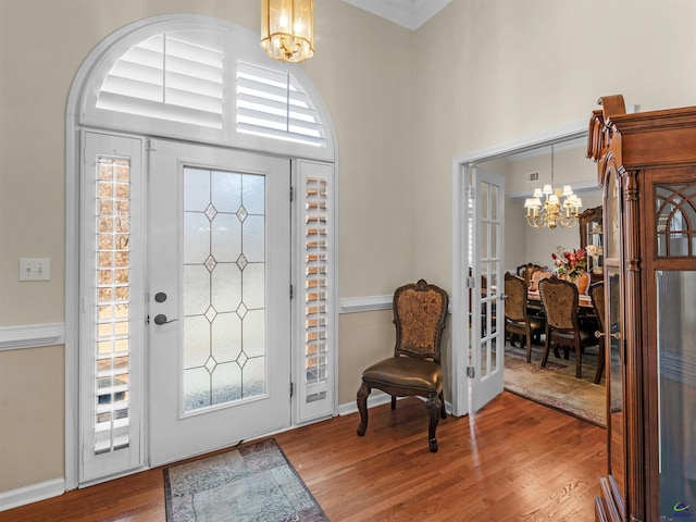 entryway with a towering ceiling, a chandelier, and hardwood / wood-style floors