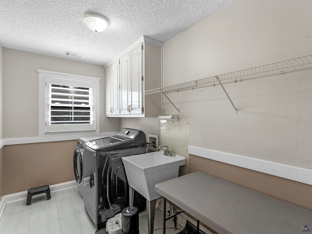 laundry area with cabinets, independent washer and dryer, sink, and a textured ceiling