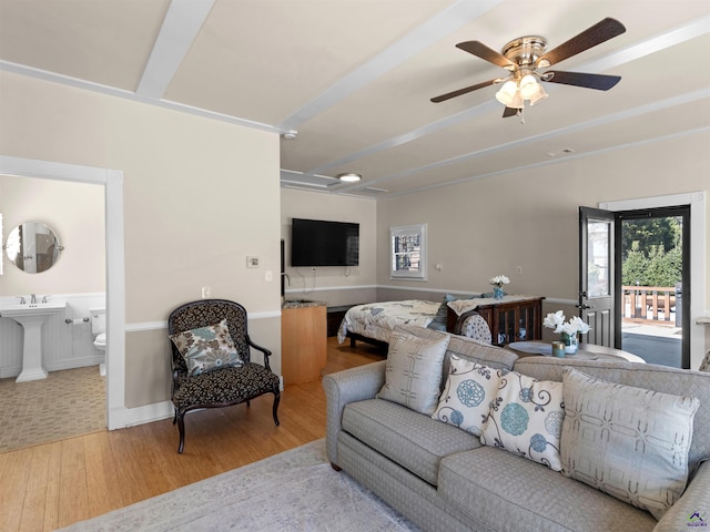 living room featuring beamed ceiling, light hardwood / wood-style floors, and ceiling fan