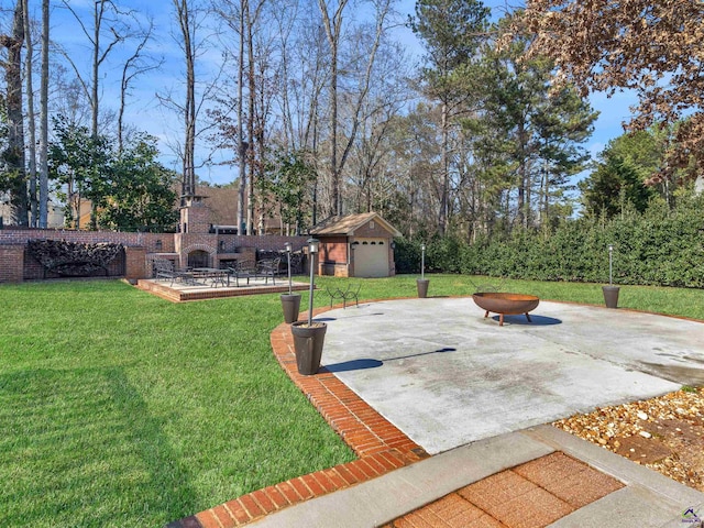 view of yard featuring exterior fireplace, a garage, an outdoor structure, and a patio