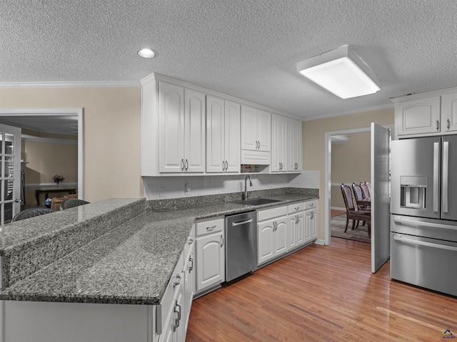 kitchen with sink, light hardwood / wood-style flooring, ornamental molding, stainless steel appliances, and white cabinets