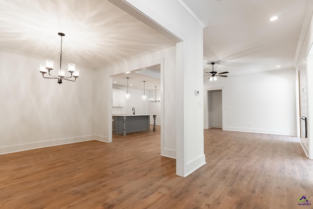 interior space featuring baseboards, light wood-style flooring, recessed lighting, ornamental molding, and ceiling fan with notable chandelier