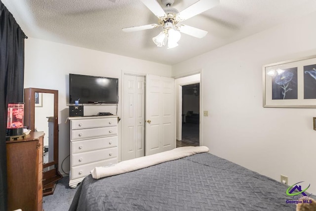 carpeted bedroom with ceiling fan, a closet, and a textured ceiling