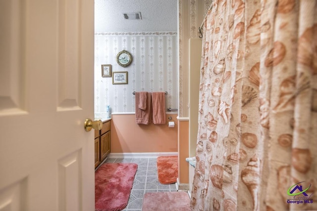 bathroom featuring tile patterned flooring and a textured ceiling