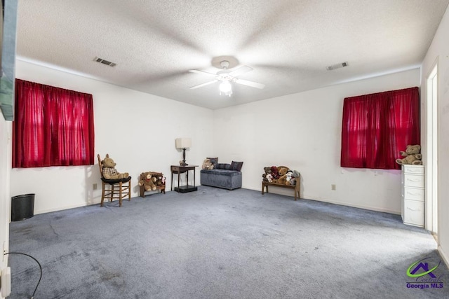 misc room with a textured ceiling, ceiling fan, and carpet flooring