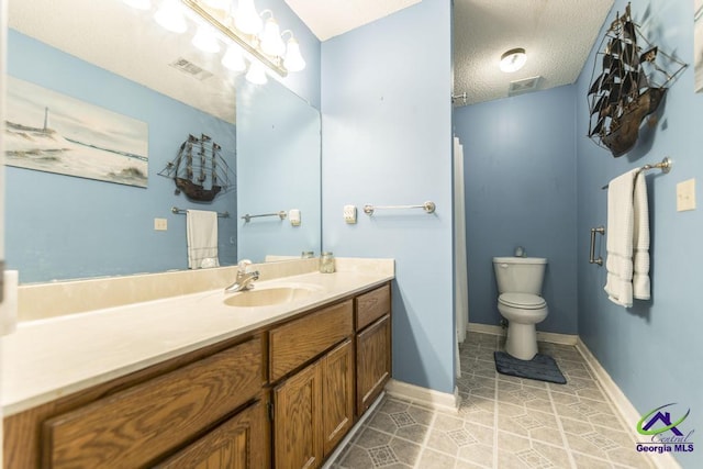 bathroom featuring tile patterned flooring, vanity, a textured ceiling, and toilet