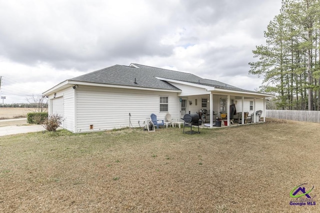 back of house featuring a garage, a lawn, and a patio area