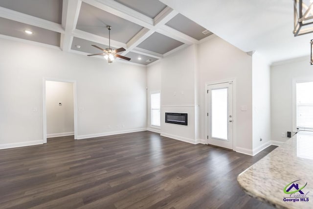 unfurnished living room with coffered ceiling, a towering ceiling, dark wood-type flooring, and beamed ceiling