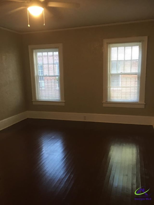 empty room with crown molding, plenty of natural light, and hardwood / wood-style flooring