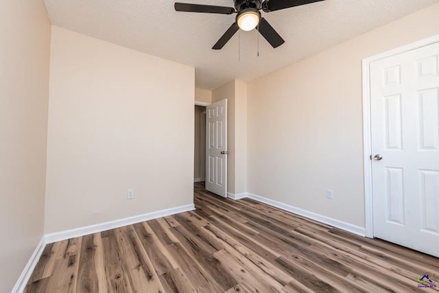 unfurnished bedroom featuring ceiling fan, dark wood-type flooring, and a textured ceiling