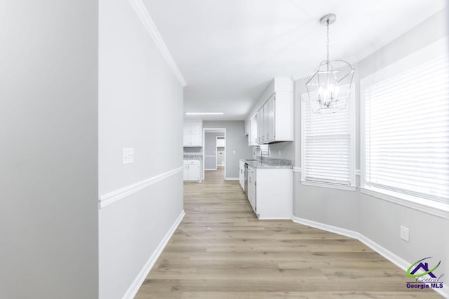 kitchen with sink, hanging light fixtures, a notable chandelier, white cabinets, and light wood-type flooring