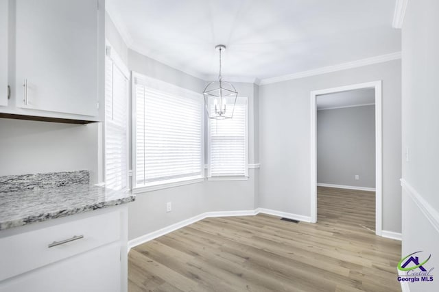 dining space with ornamental molding, light hardwood / wood-style floors, and a notable chandelier