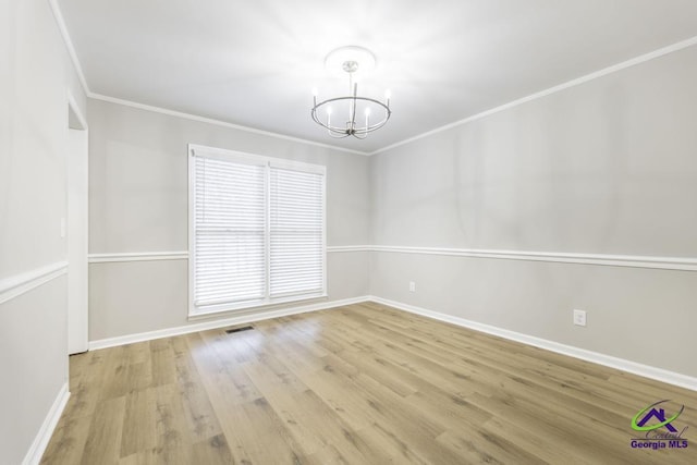 spare room featuring an inviting chandelier, crown molding, and light hardwood / wood-style floors