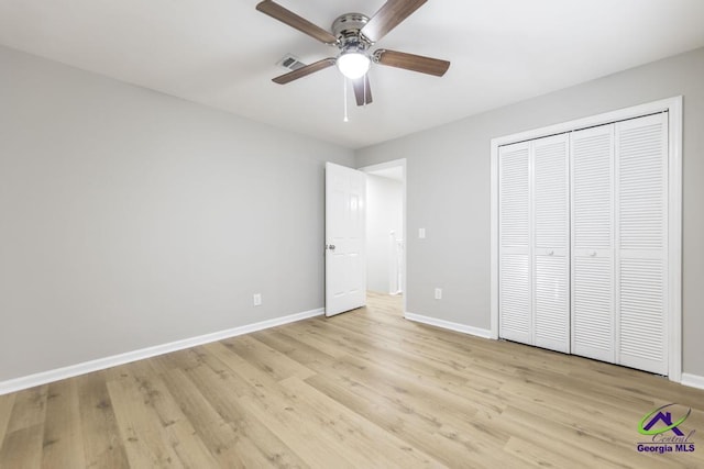 unfurnished bedroom featuring ceiling fan, a closet, and light wood-type flooring