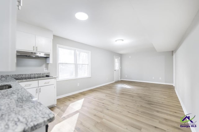 kitchen with white cabinetry, black electric stovetop, light stone counters, and light hardwood / wood-style flooring