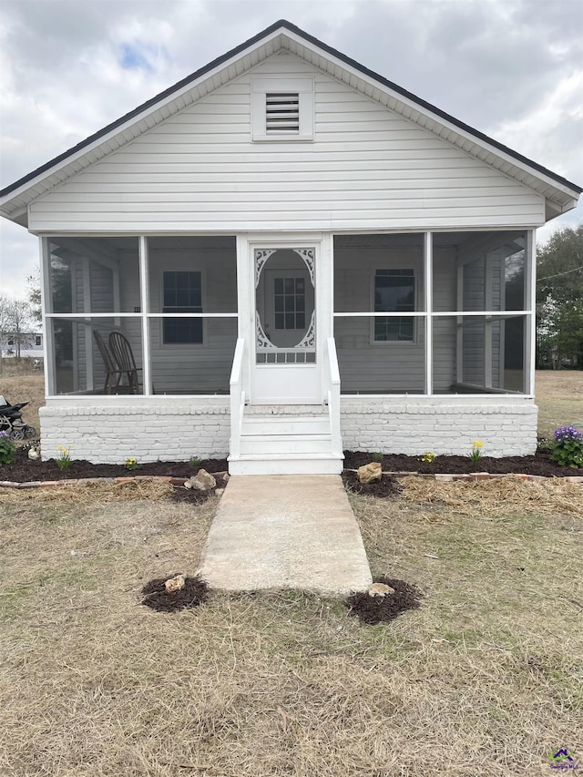 bungalow-style home with a front yard and a sunroom