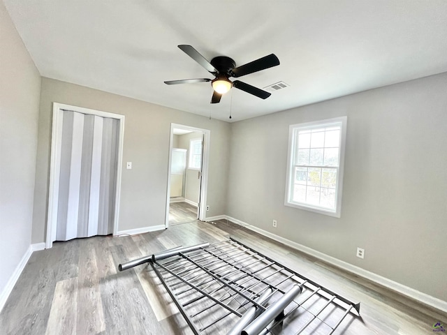 unfurnished bedroom featuring a closet, light hardwood / wood-style floors, and multiple windows