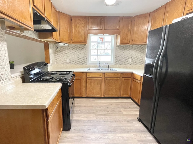 kitchen featuring sink, backsplash, light wood-type flooring, and black appliances