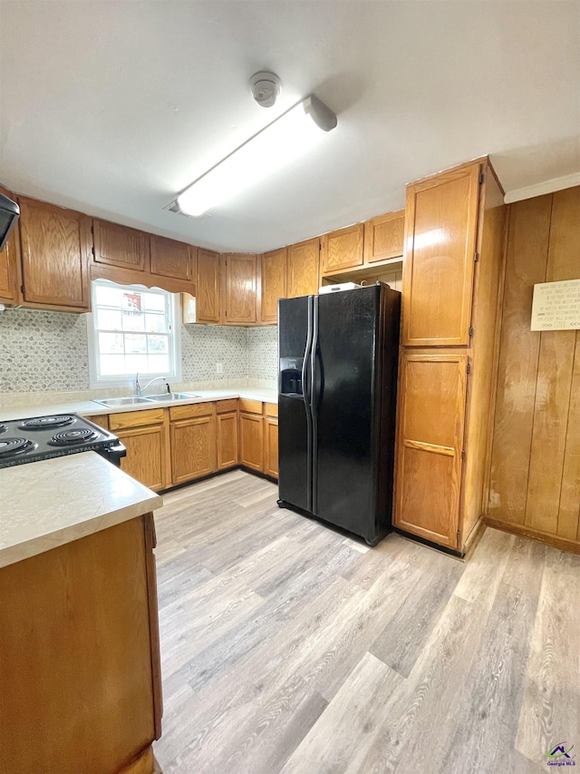 kitchen with tasteful backsplash, sink, light hardwood / wood-style flooring, and black appliances