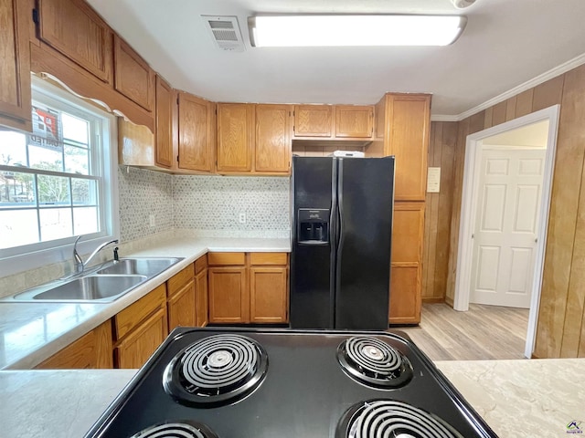 kitchen with sink, range, backsplash, ornamental molding, and black fridge