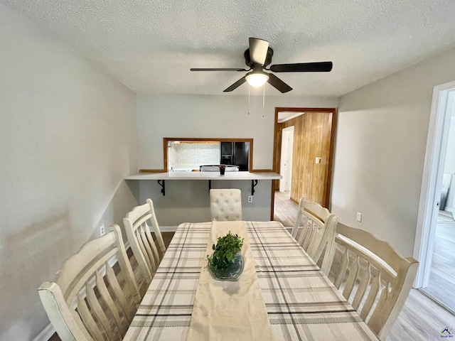 dining room with ceiling fan, a textured ceiling, and light wood-type flooring