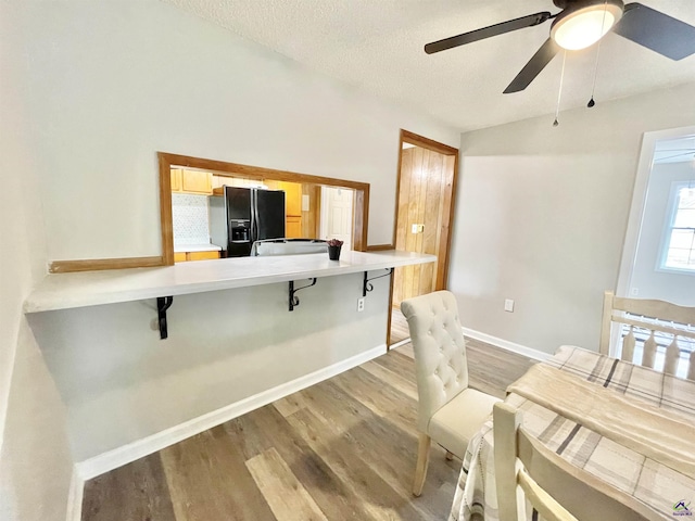 dining room featuring ceiling fan, lofted ceiling, light hardwood / wood-style floors, and a textured ceiling