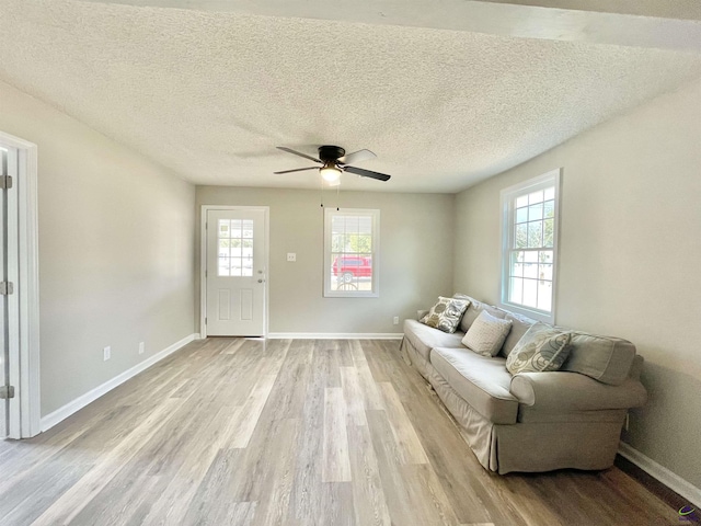 living room featuring ceiling fan, a wealth of natural light, light hardwood / wood-style floors, and a textured ceiling