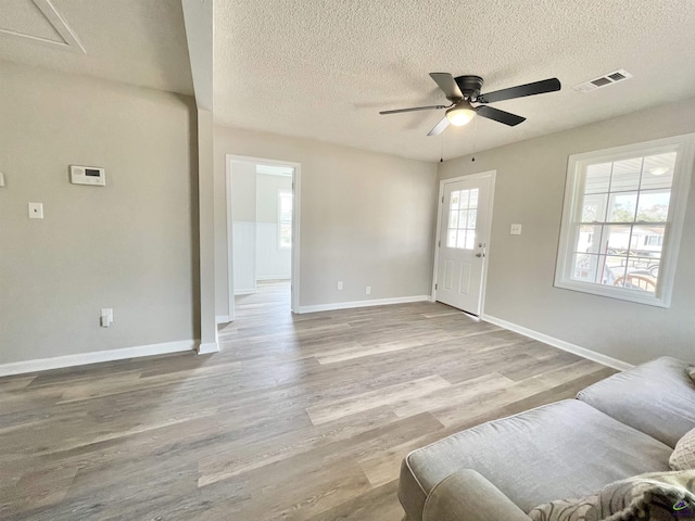 living room with a textured ceiling, light hardwood / wood-style floors, and ceiling fan