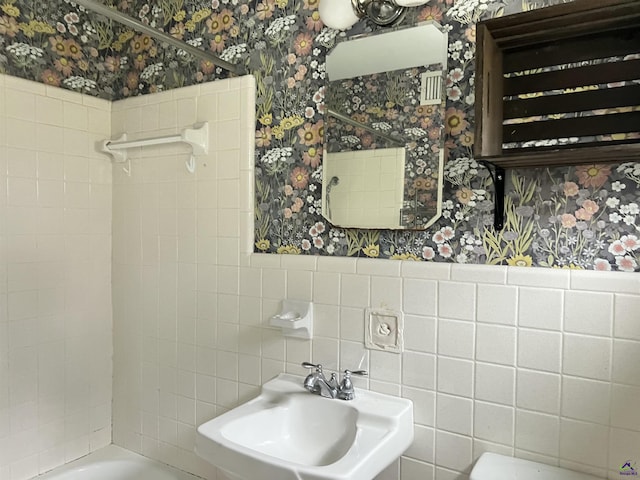 bathroom featuring tiled shower / bath, sink, and tile walls