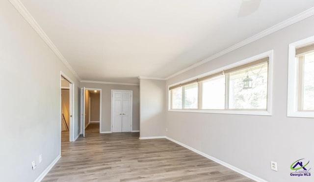 empty room featuring ornamental molding and light wood-type flooring