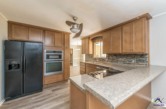 kitchen with light hardwood / wood-style floors, appliances with stainless steel finishes, kitchen peninsula, and sink