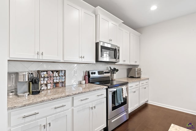 kitchen featuring appliances with stainless steel finishes, tasteful backsplash, light stone counters, white cabinets, and dark hardwood / wood-style flooring