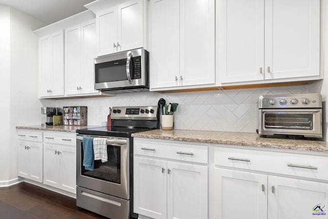 kitchen featuring appliances with stainless steel finishes, dark hardwood / wood-style floors, tasteful backsplash, white cabinetry, and light stone countertops