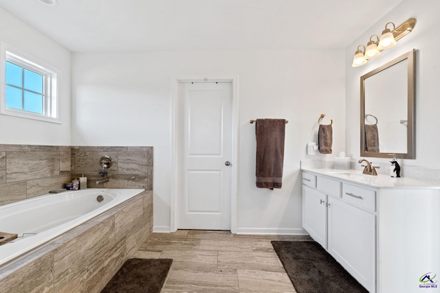 bathroom featuring vanity, hardwood / wood-style floors, and a relaxing tiled tub