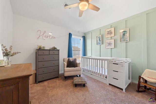 bedroom with a nursery area, ceiling fan, and light carpet