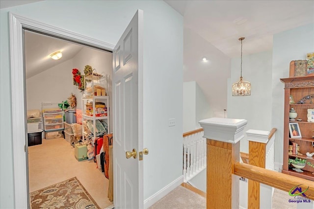 corridor with vaulted ceiling, carpet flooring, and a notable chandelier