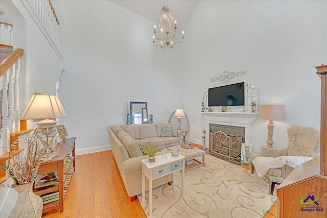 living room featuring a notable chandelier, a towering ceiling, and light wood-type flooring