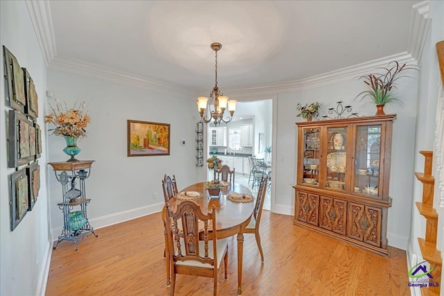 dining area with ornamental molding, an inviting chandelier, and light hardwood / wood-style floors