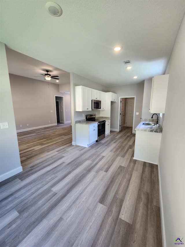 111 Silver Maple, Byron, GA 31008 - kitchen featuring light wood-style flooring, stainless steel appliances, open floor plan, white cabinetry, and baseboards