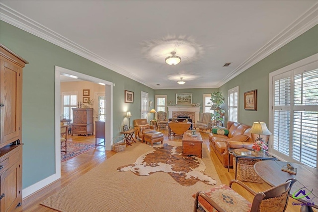 living room with ornamental molding, a fireplace, light hardwood / wood-style floors, and a healthy amount of sunlight