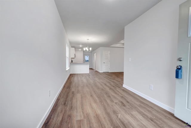 unfurnished living room with an inviting chandelier and light wood-type flooring