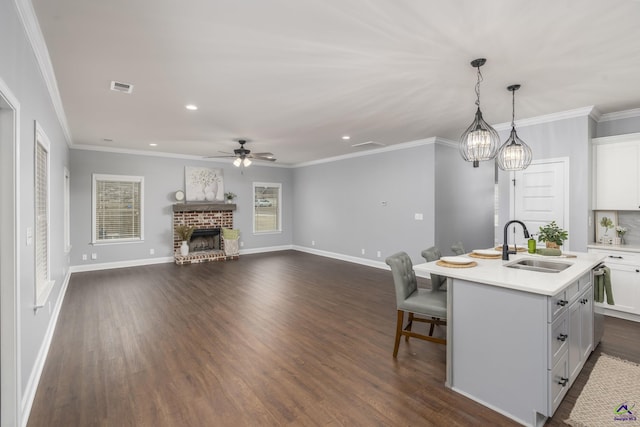 kitchen with sink, decorative light fixtures, a center island with sink, dark hardwood / wood-style flooring, and a fireplace