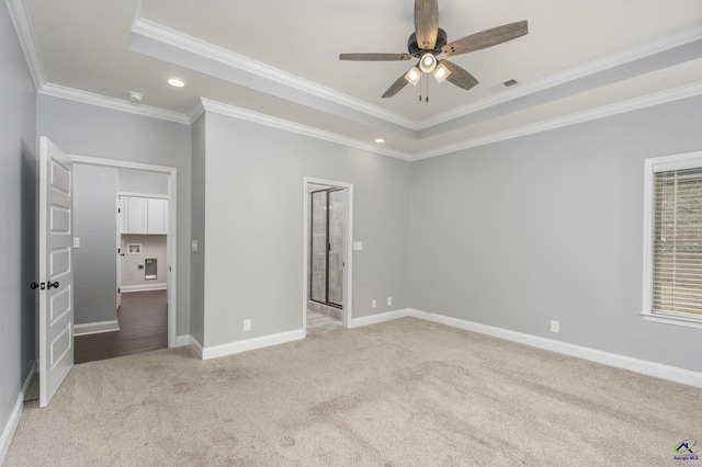 unfurnished bedroom with crown molding, light colored carpet, and a tray ceiling