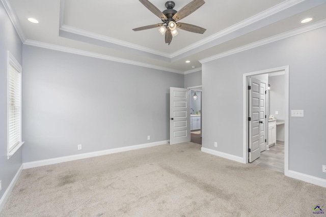 unfurnished bedroom with ornamental molding, light carpet, and a tray ceiling